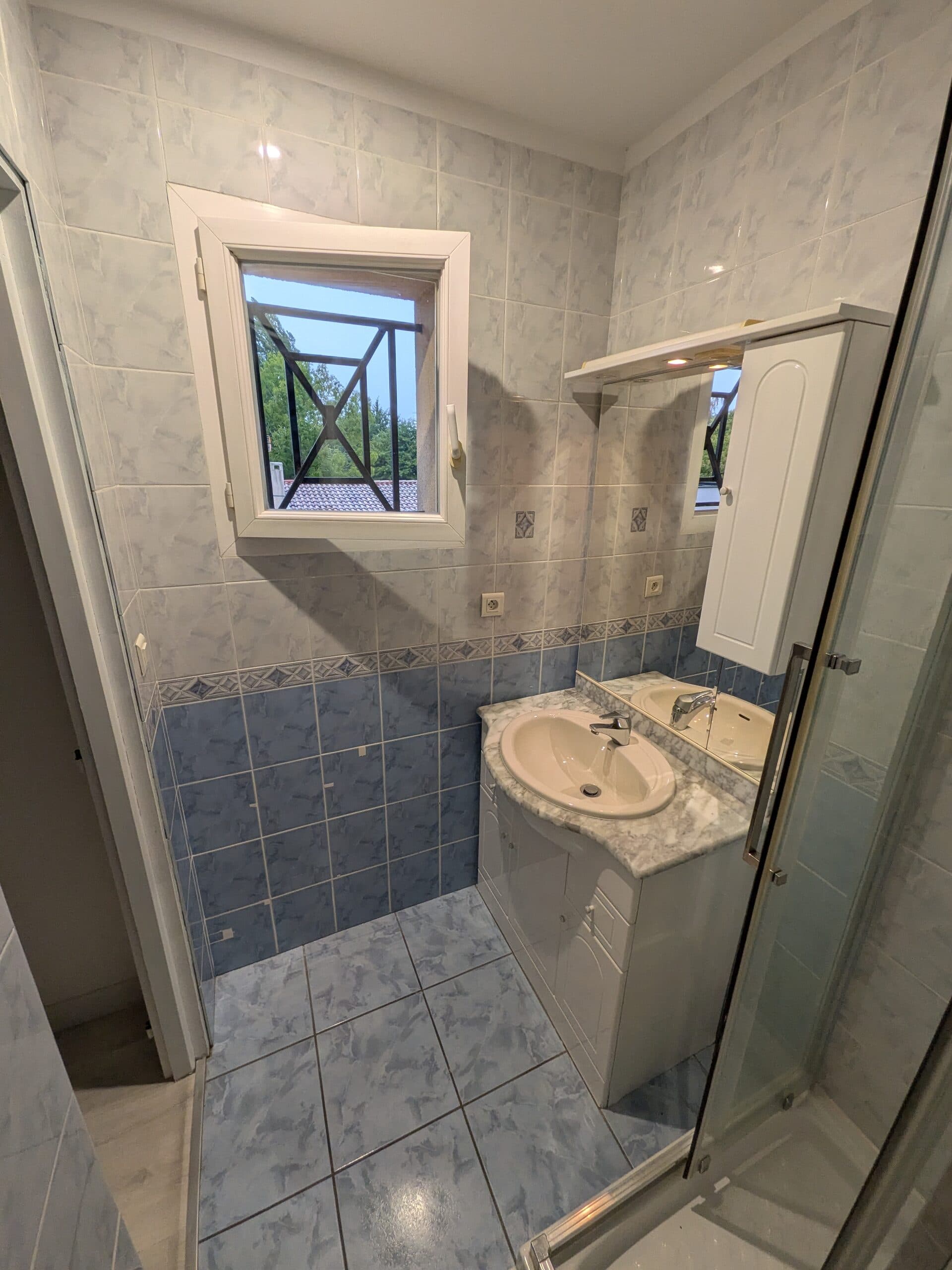 Seconde salle de bain avant travaux, meuble vasque sous la fenêtre et faïence bleue d'origine