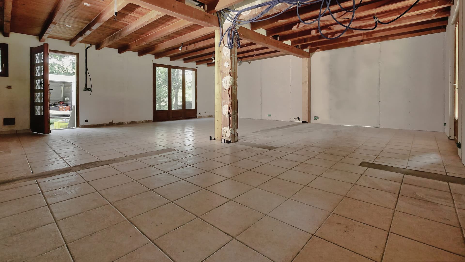 Ancien carrelage beige de la pièce à vivre avant travaux, bandes laissées au sol par les cloisons démolies