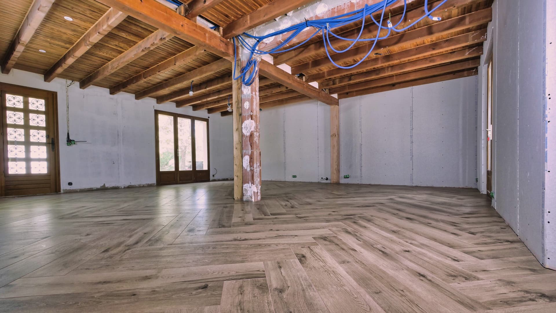 Même vue après la pose, carrelage effet chêne 20x120 en bâton rompu sur toute la pièce à vivre sous poutres apparentes