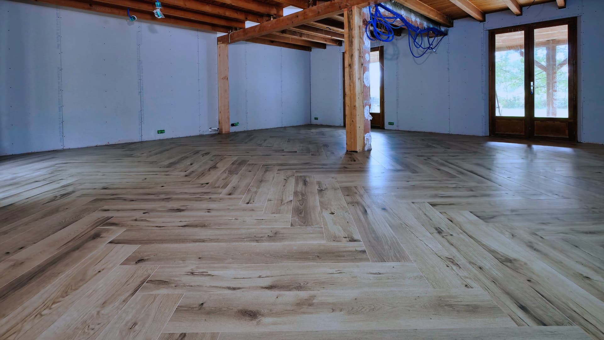 Motif en bâton rompu du carrelage imitation parquet vu dans la longueur de la pièce, vers les portes-fenêtres