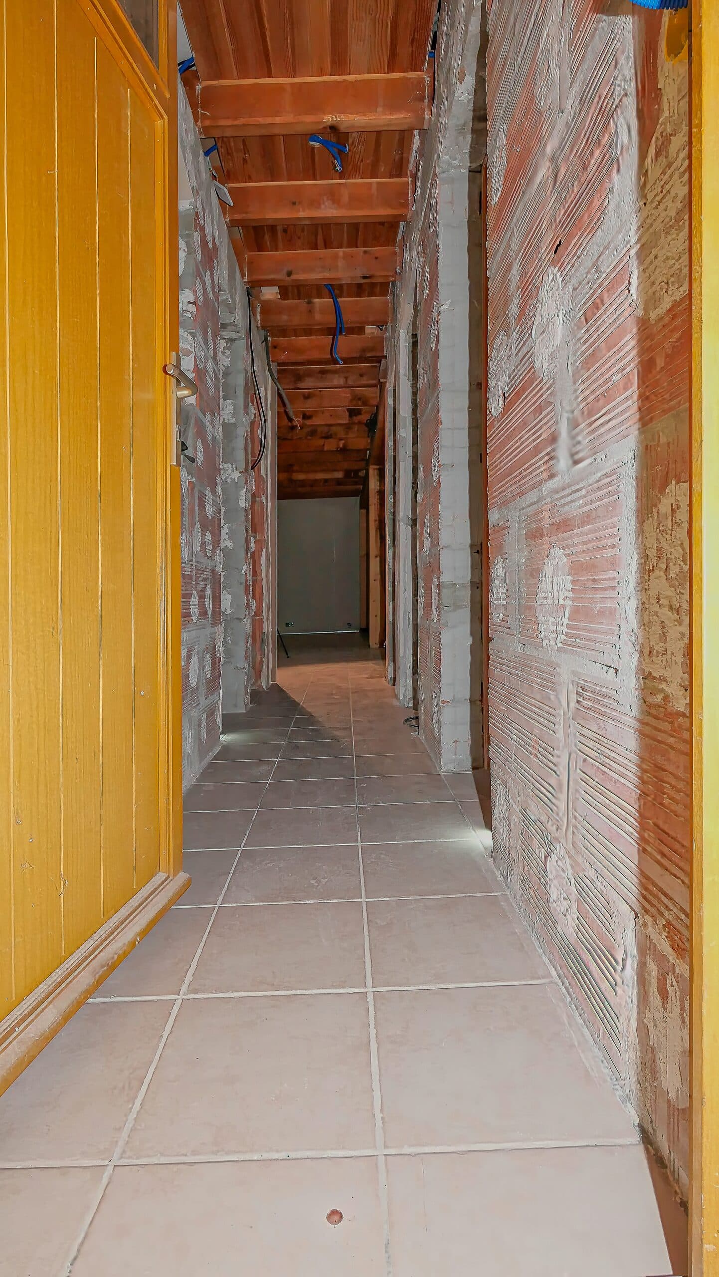 Couloir avant travaux, ancien carrelage beige entre les cloisons en brique