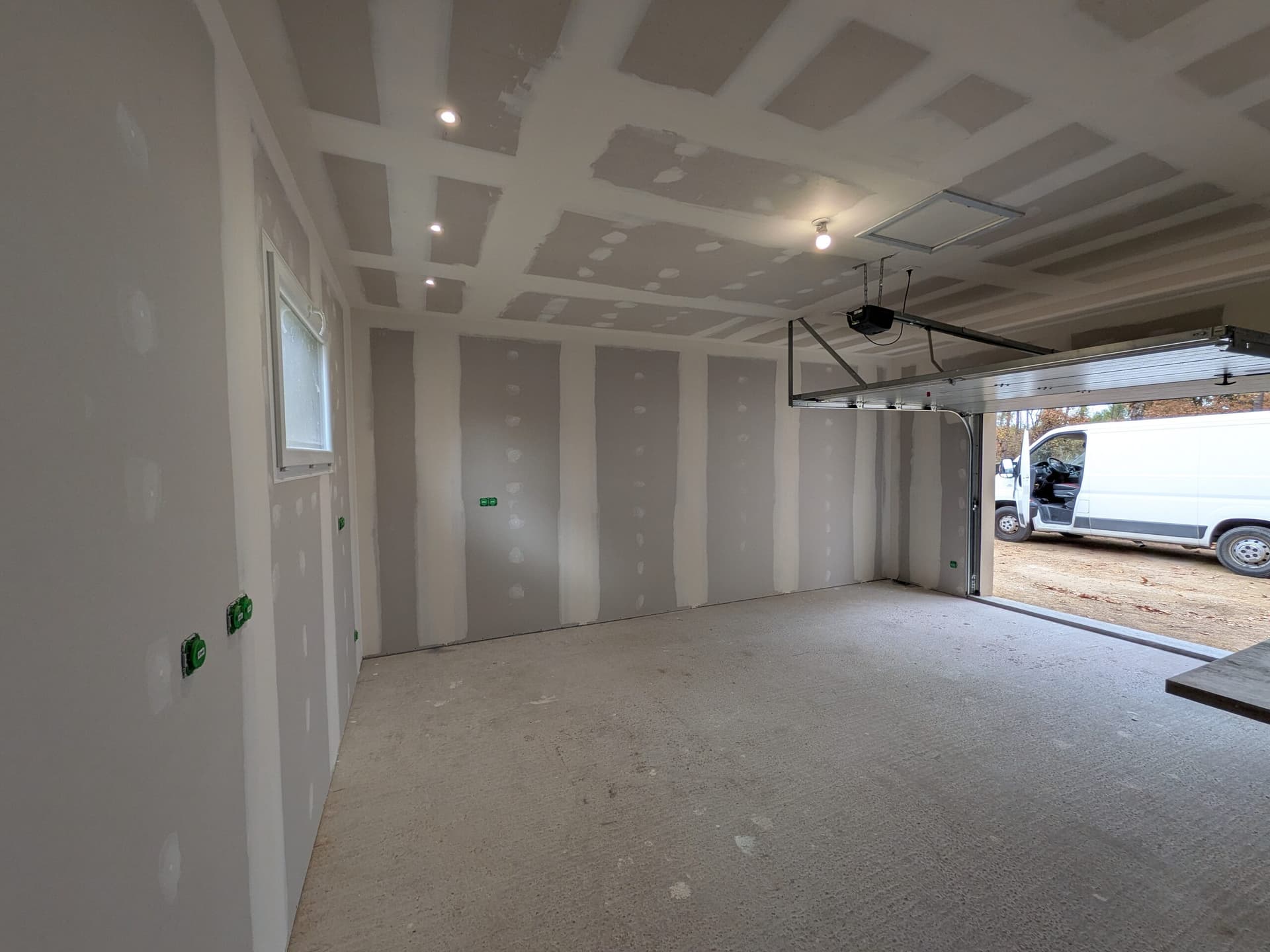 Garage terminé vu en diagonale, spots allumés et bandes faites sur le grand mur et le mur de la fenêtre