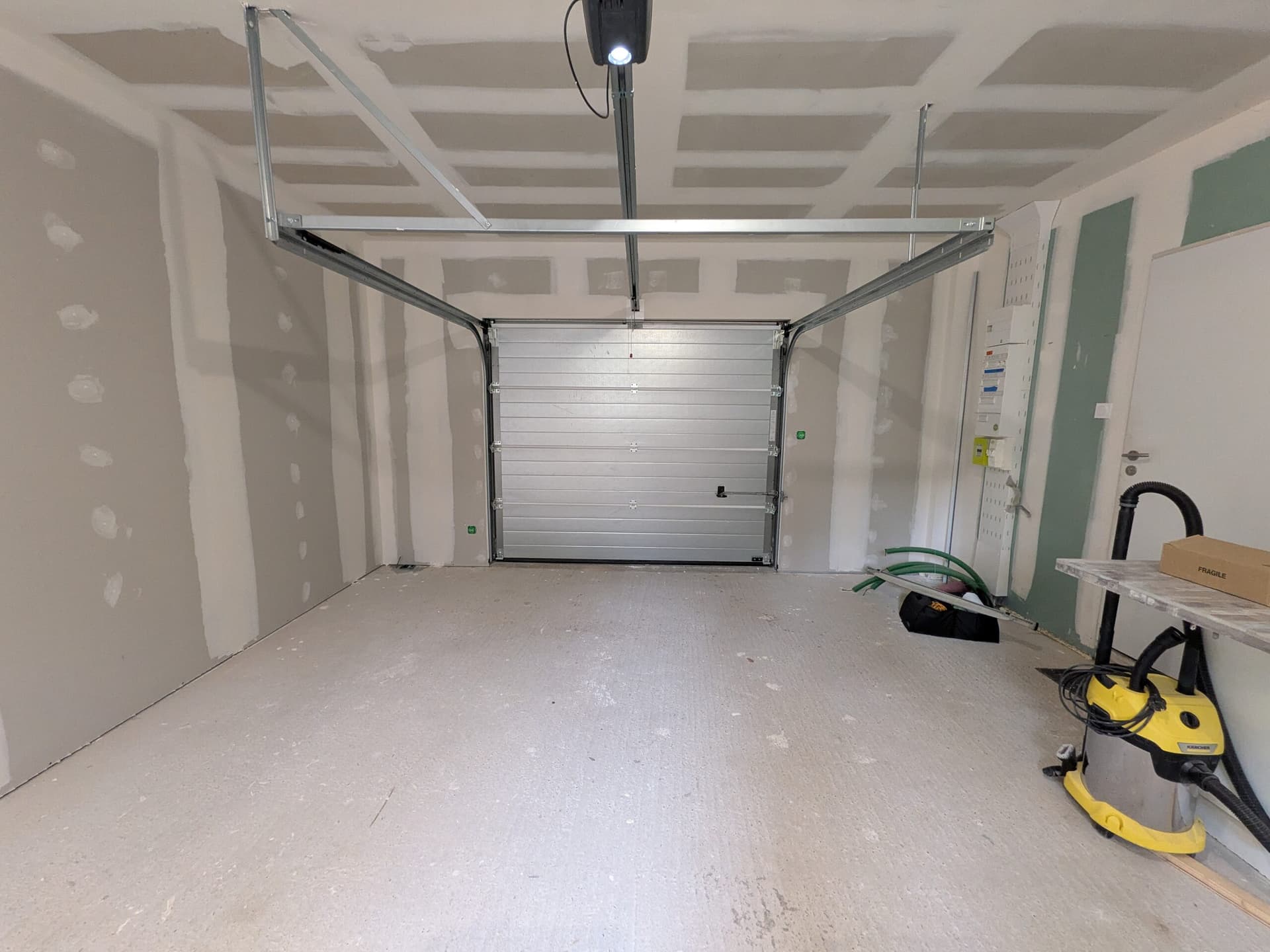Garage terminé vu vers la porte sectionnelle fermée, murs doublés et bandés