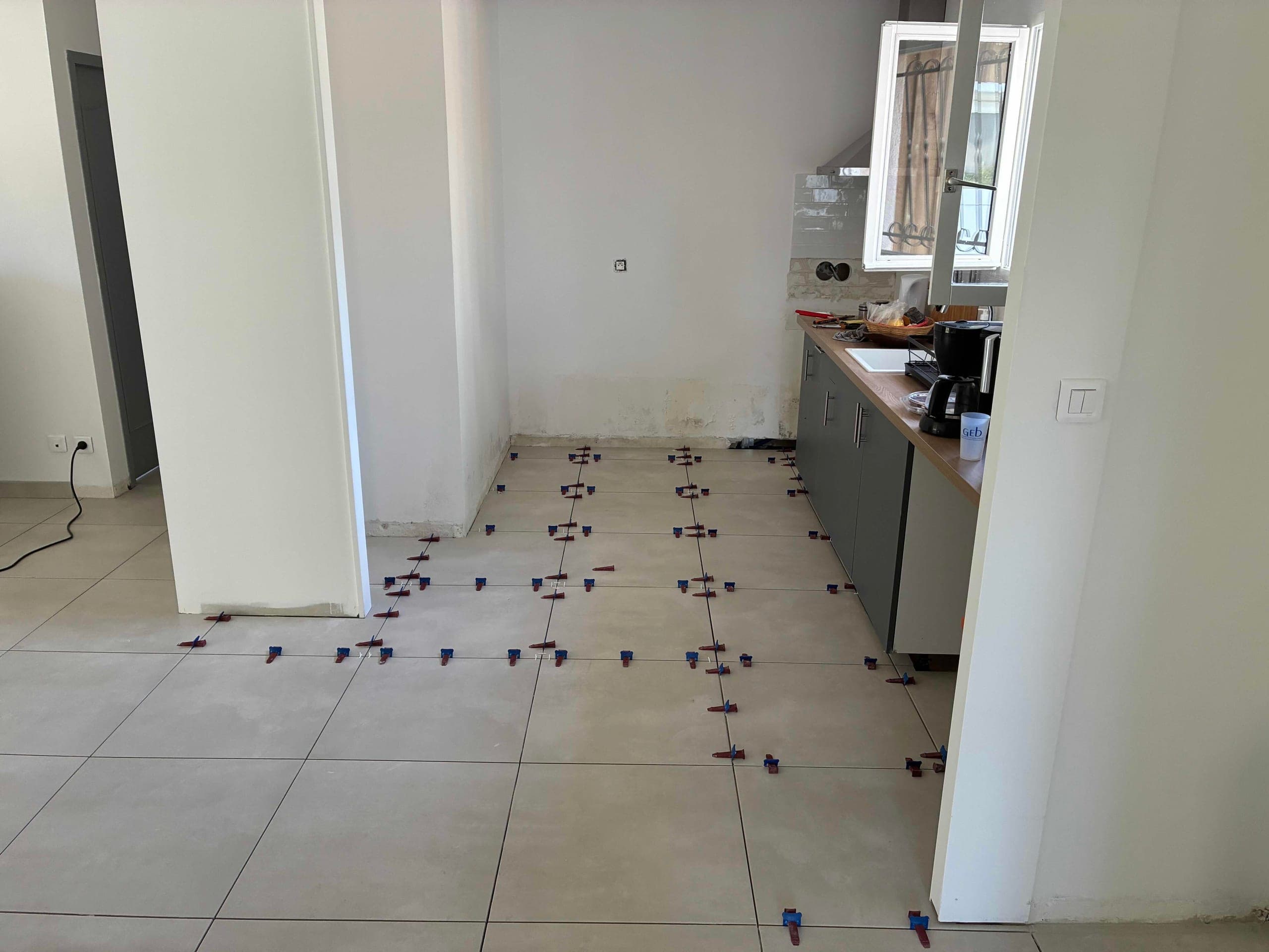 Pose du carrelage en direction de la cuisine, croisillons autonivelants le long des joints