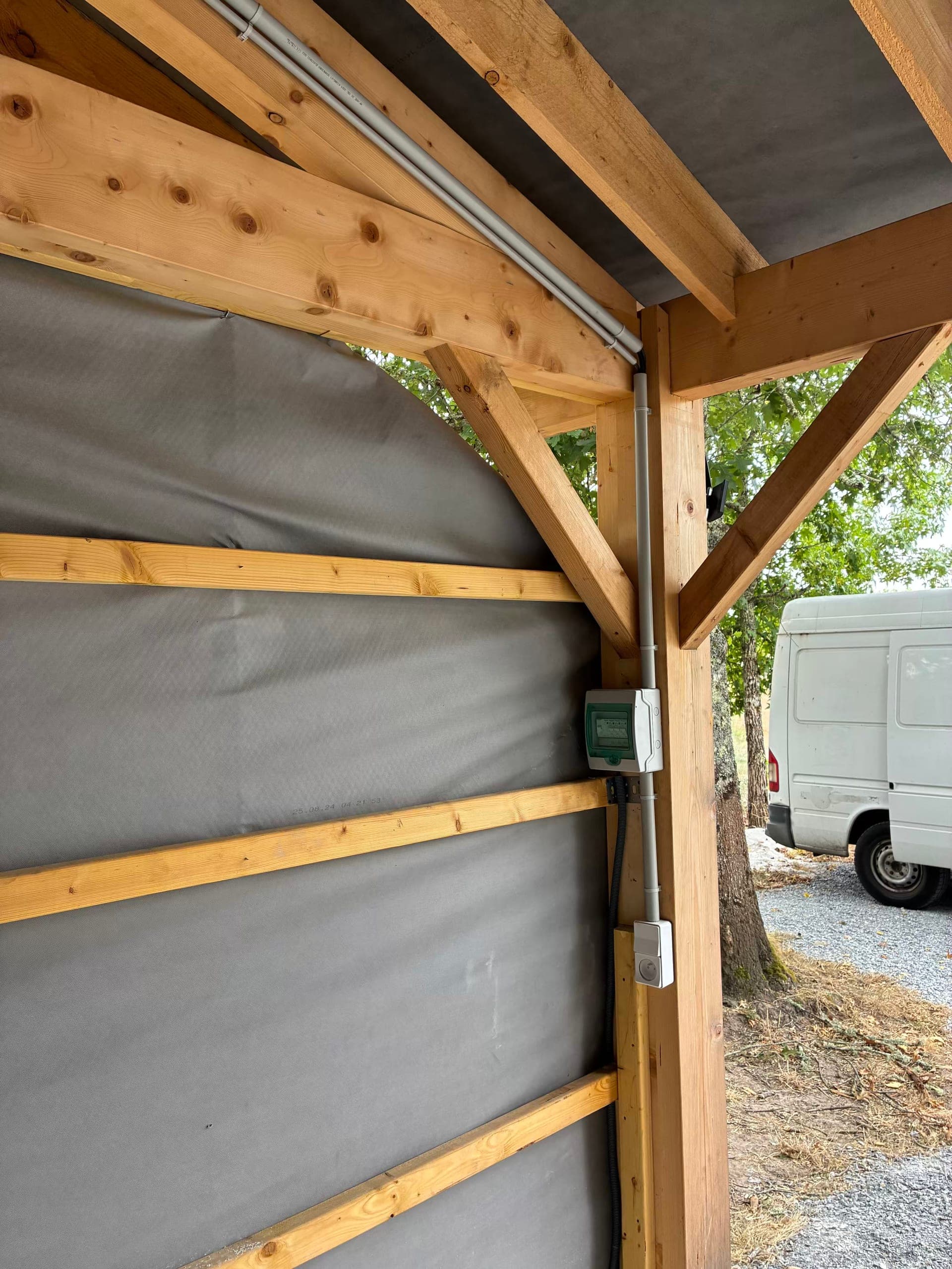 Tableau divisionnaire et prise de courant fixés sur le poteau du garage bois, alimentation montant en tube IRL