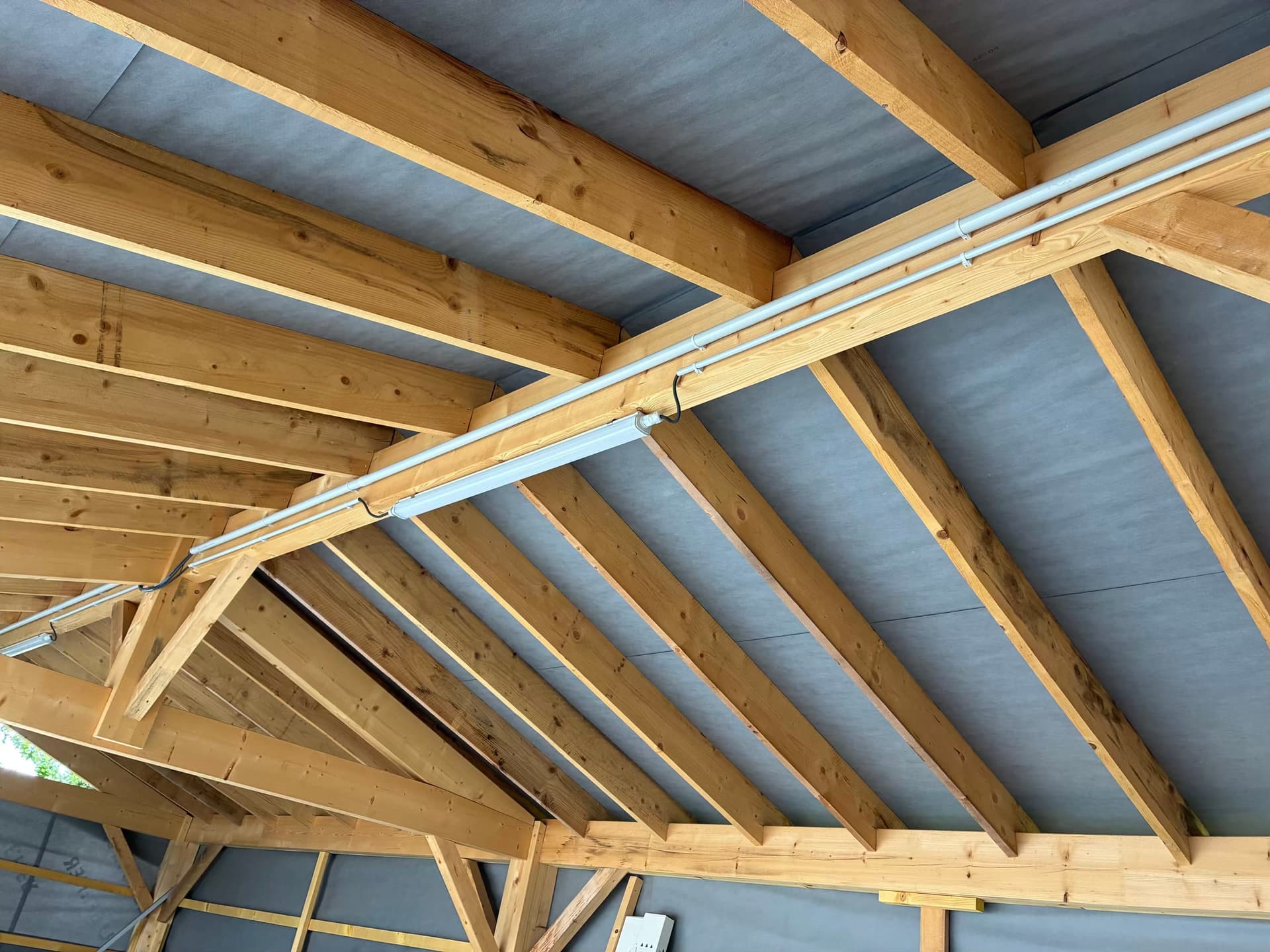 Réglette LED et tubes IRL fixés le long de la charpente du garage à ossature bois